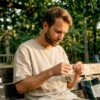 Un homme assis à une table examine un sachet de fleurs de CBD.
