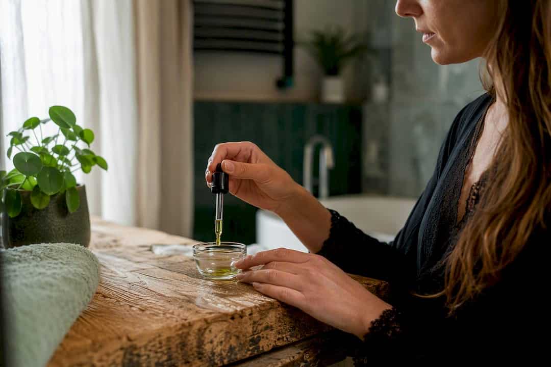 Des mains versant de l'huile de CBD pour soulager les douleurs menstruelles