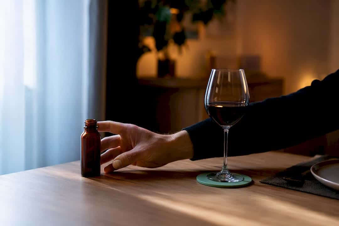 Flacon de CBD tenu à l'écart d'un verre de vin