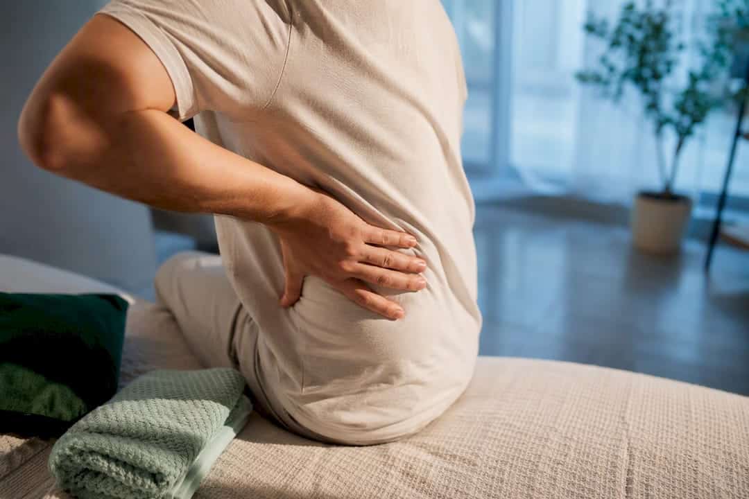 Personne massant délicatement le bas du dos