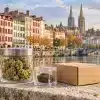CBD Bayonne : le guide essentiel des fleurs et des résines 4 CBD Bayonne : fleurs de chanvre, résine et colis devant une évocation des quais de la Nive et de la cathédrale Sainte-Marie.